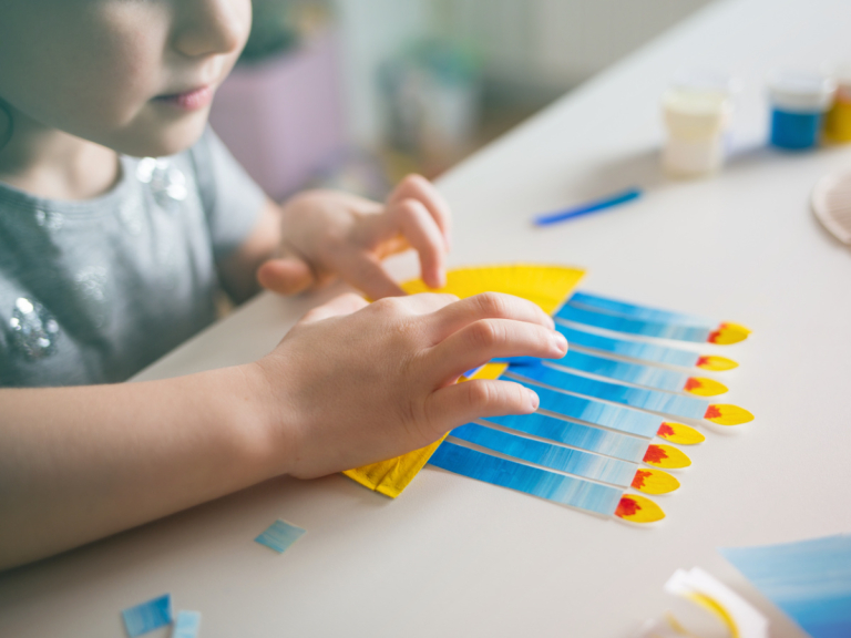 Kid making a craft menorah with eight lighted candles.